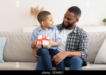 Black Daddy Congratulating Kid Son Giving Birthday Gift At Home Stock Photo