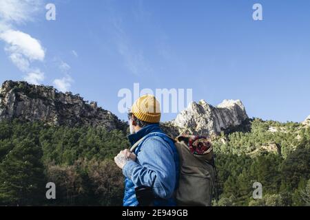 Man with backpack hiking in the mountains on a warm sunny spring day Stock Photo