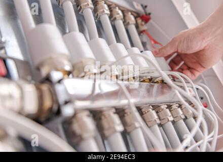 Modern Home Water Heating Valves Adjusting by Caucasian Men. Row of Valves Close Up. Stock Photo