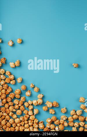 Popcorn is scattered on a blue background, in the form of a frame. Yummy for the filming of movies, TV series, cartoons. Free space, top view Stock Photo