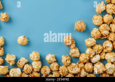 Popcorn is scattered on a blue background, in the form of a frame. Yummy for the filming of movies, TV series, cartoons. Free space, top view Stock Photo