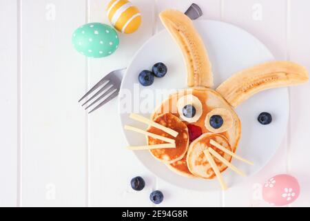 Fun Easter Bunny pancakes on a white plate. Close up table scene against a white wood background. Stock Photo