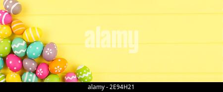Colorful Easter banner with Easter Egg corner border against a yellow wood background. Top view with copy space. Stock Photo