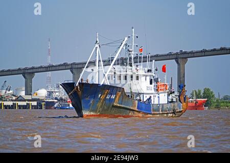 Commercial fishing boat / trawler sailing under the Jules Wijdenbosch Bridge / Bosje Brug on the Suriname River at Paramaribo, Suriname / Surinam Stock Photo