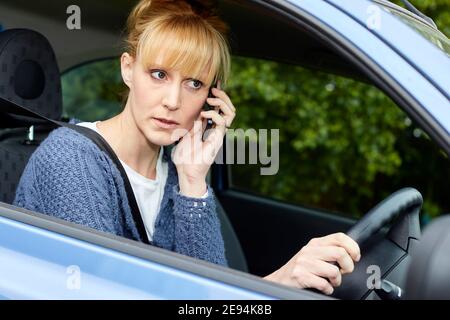 Woman driving whilst using mobile phone Stock Photo