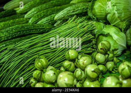Close-up of fresh vegetables / greens / cabbages, eggplants and yardlong beans at the Centrale Markt / central market in Paramaribo, Suriname Stock Photo