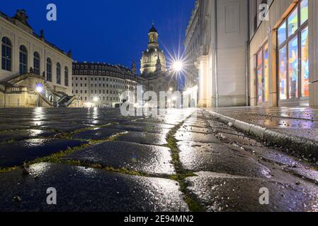 Dresden, Germany. 02nd Feb, 2021. The lights on Neumarkt and a restaurant offering takeaway food reflect on the cobblestones in the evening in front of the Frauenkirche (M) and the Museum of Transport (l). Credit: Robert Michael/dpa-Zentralbild/ZB/dpa/Alamy Live News Stock Photo