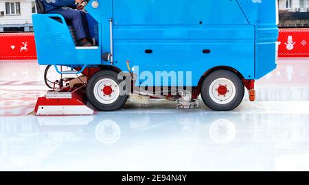 A stadium worker cleans an ice rink on a blue modern ice cleaning machine, copy space. Stock Photo