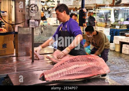 TOKYO, JAPAN - MAY 11, 2012: Vendor cuts large frozen tuna fish at Tsukiji Fish Market in Tokyo. It is the biggest wholesale fish and seafood market i Stock Photo