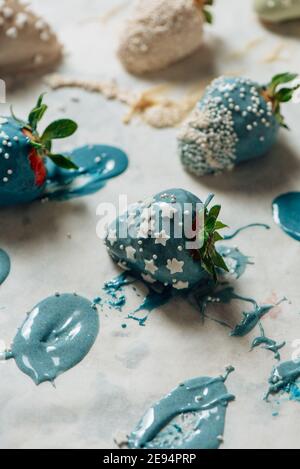 Step by step. Tasty Blue and white chocolate dipped strawberries with sugar sprinkles on a parchment paper Stock Photo