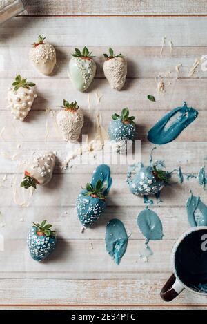 Step by step. Tasty Blue and white chocolate dipped strawberries with sugar sprinkles on a parchment paper. valentine´s day; Stock Photo