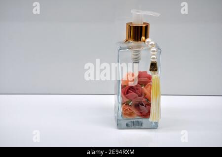 Transparent perfume glass with colorful rose petals with spray cap on white background with copy space Stock Photo