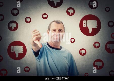 Displeased middle aged man shows thumbs down, negative gesture and bad feedback. Rejection and refusal, dislike symbol. Senior male frustrated as cust Stock Photo