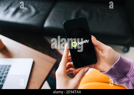 Hand holding iPhone with Spotify app logo on the screen Stock Photo