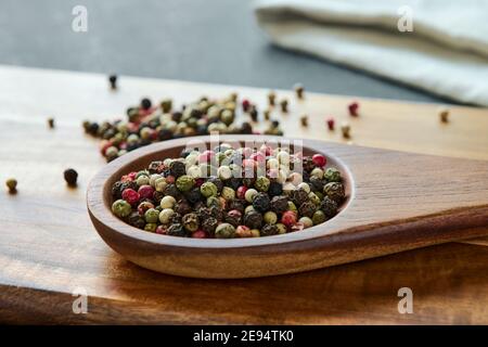 Variety of colored peppercorns on a wooden spoon, spice, macro Stock Photo