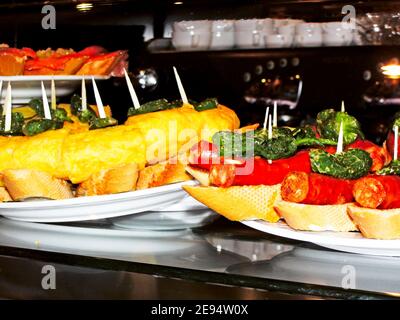 Spanish tapas of potato omelette and chorizo with fried peppers on top and bread base Stock Photo