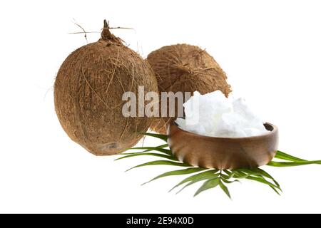 Coconut organic pure oil. Coconut oil in a wooden cup and coconuts fruits with green palm leaf isolated on white background Stock Photo