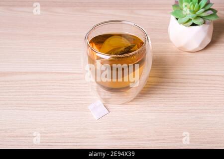 Hot green tea in double walled glass with tea bag on table Stock Photo