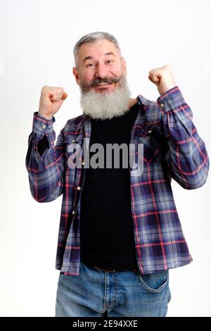 Studio portrait of mature bearded man in casual clothes raised his hands up, gesture of victory and joy, yes sign, white background Stock Photo