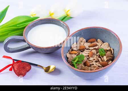 Spelt flakes with milk on breakfast. Light breakfast on Valentine's day with tulips and heart Stock Photo