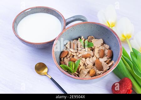 Spelt flakes with milk on breakfast. Light breakfast on Valentine's day with tulips and heart Stock Photo