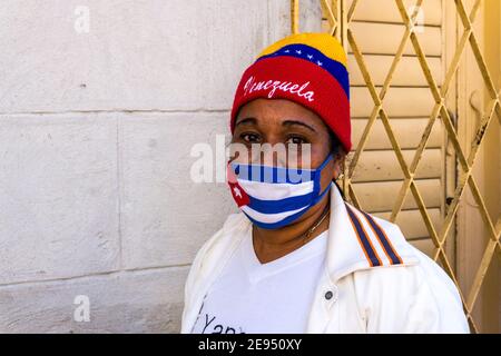 Cuban Afro-Caribbean woman wearing a protective face mask with the Cuban flag and a hat with the Venezuelan flag. It is the time of the Covid-19 in Sa Stock Photo