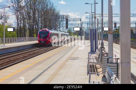 The train arrives at the station platform. The locomotive of the red train arrives at the platform Stock Photo