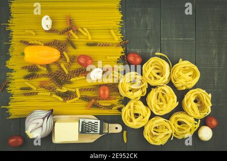 Dry Spaghetti and homemade noodles are laid out on the table. Background with place for text. Pasta and spices are sprinkled on the table on the table Stock Photo