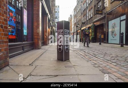 London, UK. 2nd Feb, 2021. A man wearing a face mask as a precaution against the spread of coronavirus walks past a 'Stop The Spread Of Coronavirus' sign in Covent Garden, London.The coronavirus lockdown remains in place across the UK as the nation continues to struggle with the pandemic. Credit: Vuk Valcic/SOPA Images/ZUMA Wire/Alamy Live News Stock Photo