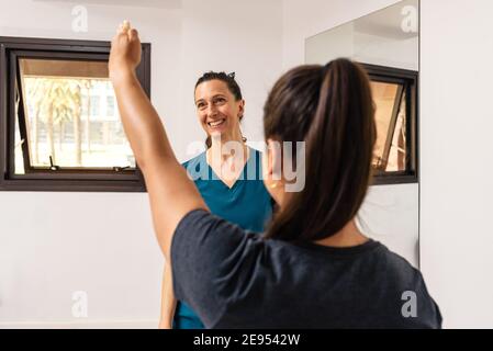 Stock photo of unrecognized woman doing rehabilitation exercises with professional worker. Stock Photo