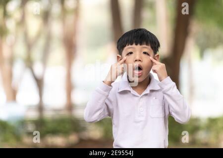 Asian child enjoying making a funny face. A boy with a cheeky face ...