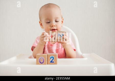 Little girl playing with wooden cubes with bright numbers 2022