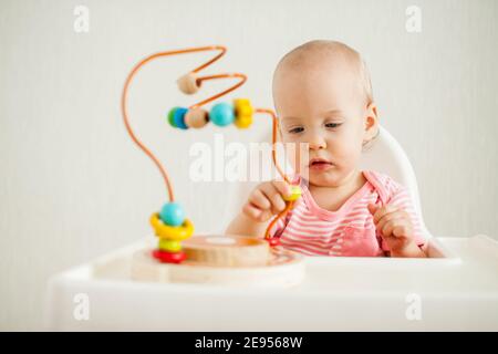 little girl plays with an educational maze toy. Development of fine motor skills and logical thinking Stock Photo