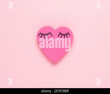 Heart shape pink paper with eyelashes. Valentines or woman's day background design. Minimal flat lay. Stock Photo