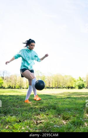 Portrait of young woman practicing soccer skills and doing tricks with the football ball. Soccer player juggling the ball. Sports concept. Stock Photo