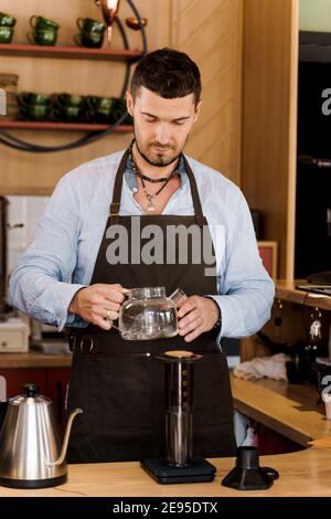 Aeropress coffee: barista press to device and coffee drops pours trought  aeropress to pot. Alternative coffee brewing method. Vertical photo  handsome Stock Photo - Alamy