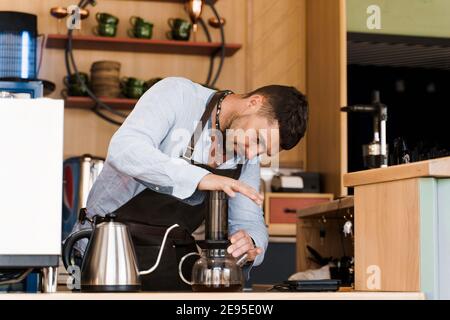 Aeropress coffee: barista press to device and coffee drops pours trought  aeropress to pot. Alternative coffee brewing method. Vertical photo  handsome Stock Photo - Alamy