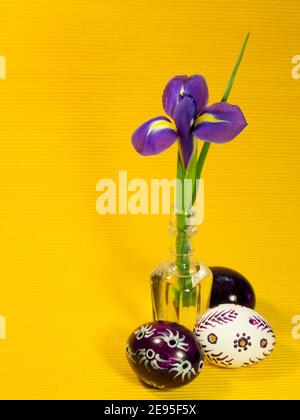 Iris in glass bottle and three easter eggs Stock Photo
