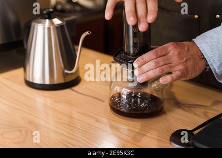 Aeropress coffee close-up: barista press to device and coffee drops pours  trought aeropress to pot. Alternative coffee brewing method. Vertical photo  Stock Photo - Alamy