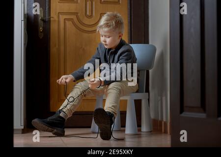 Child tying his shoes before leaving home, selective focus Stock Photo