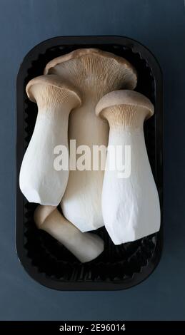 Eringi mushrooms in plastic packaging on a gray background. Pleurotus eringi. Vegetarian food concept. flat lay Stock Photo