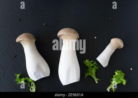 Eringi mushrooms with herbs on a black background. Pleurotus eringi. Vegan food concept. flatlay. Stock Photo