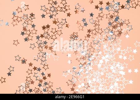 Gold and silver star dust sparkle on orange. Chaotic cosmic background with gold star elements flying. Gold glitter dust confetti, magic shining sparkles scatter. Starry festive decor. Stock Photo