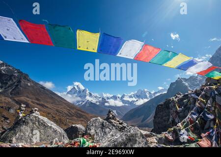 Holy buddhist praying multicolored flags with mantras flapping and waving on the strong wind with valley view and Ama Dablam 6812m peak.Everest Base C Stock Photo