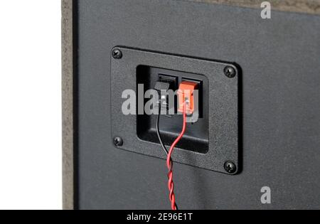 Red and black twisted wire connected to connection socket on rear side of speaker system box side view studio photo isolated on white close up Stock Photo