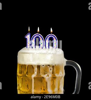 number 100 candle in beer mug for birthday celebration isolated on black Stock Photo