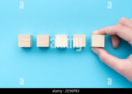 Hand holding a row of five blank wooden cubes Stock Photo