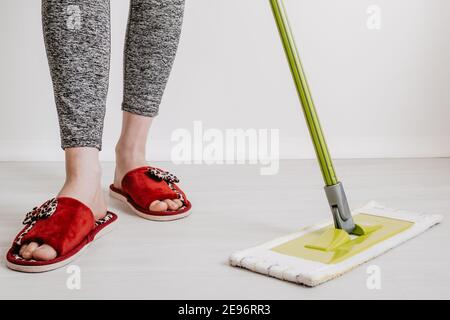 House cleaning concept. Close-up of a mop and female feet in house slippers. Space for text. Stock Photo