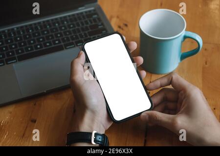 Mockup image blank white screen cell phone.men hand holding texting using mobile relax on sofa at home. background empty space for advertise text Stock Photo