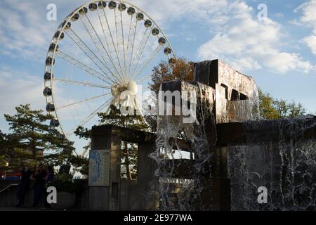 Seattle, WA-11.28.18: Seattle's Great Ferris Wheel near Pike Place market and the Seattle aquarium; a geometric fountain is seen sprouting water. Stock Photo